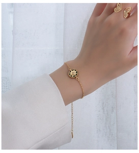 Close-up of a gold eight-pointed star zircon charm bracelet on a model's wrist