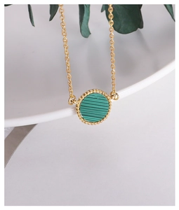 Detailed view of gold necklace with green malachite pendant and beaded edge detail