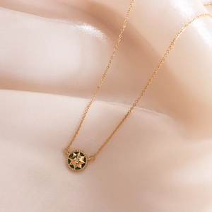 French star zircon necklace with green pendant and gold chain on satin fabric