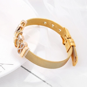 Fashionable golden mesh bracelet with sparkling rhinestone LOVE charm on white fabric
