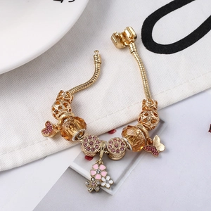 Goldenes Schlangenarmband mit rosa Schmetterling, Blumenanhängern und Kristallperlen