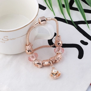 Detail van roségouden slangenarmband met roze kralen en hanger van parelmoer schelp