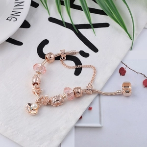 Roségouden slangenarmband met roze facetgeslepen kralen en schelpvormige hangers