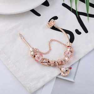 Roségouden slangenarmband met roze glazen kralen en bedeltjes van parelschelpen