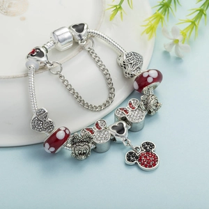 Bracelet à breloques souris argenté avec nœud rouge et perles en verre sur un plateau