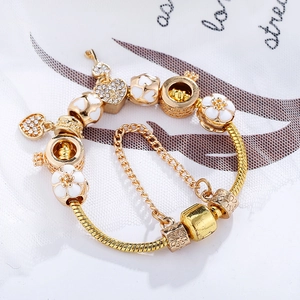 Goldenes Charm-Armband mit Herzanhänger, Schlüssel und weißer Blume an einer Schlangenkette