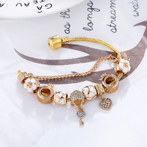 Goldenes Schlangenarmband mit Herz-Schlüssel-Anhänger und weißen Emaille-Blüten