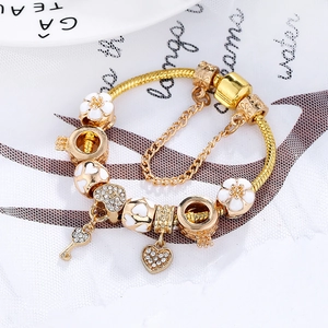 Goldenes Schlangenarmband mit weißen Emaille-Blumen, Herz-Schlüssel-Anhängern und Kronenperlen