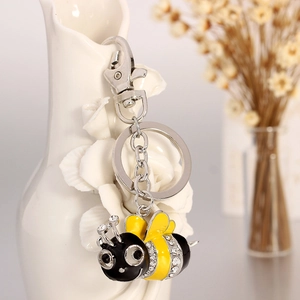 Sparkling bee keychain with crystals and yellow enamel on a white vase decorative setting