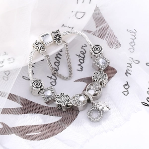 Silver charm bracelet with four-leaf clover pendant and various crystal-studded beads