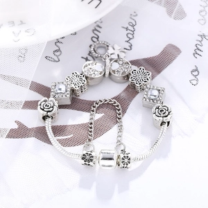 Exquisite silver charm bracelet featuring four-leaf clover pendant and floral white enamel beads