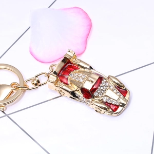 Golden racing car keychain with red enamel and sparkling rhinestones on a grid background