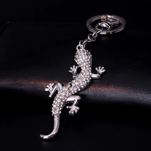 Elegant lizard keychain with sparkling rhinestones on black leather background