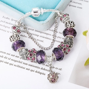 Close-up of silver snake chain bracelet with purple faceted beads and crown charm