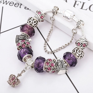 Detailed close-up of crown charm bracelet with purple glass beads and security chain