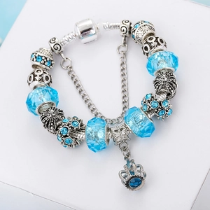 Close-up of crown pendant and blue faceted crystal beads on a silver-tone charm bracelet