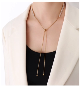 Detail van een verstelbare gouden Y-ketting met baguette-zirkonia op een echt model