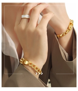 Detail eines goldenen Gliederkettenarmbands und Emaille-Rings am Handgelenk einer Frau