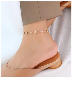 Detailaufnahme eines minimalistischen Roségold-Blumen-Fußkettchens am Knöchel mit Schuhen