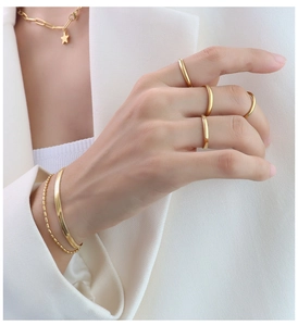 Dettaglio di anelli d'oro, bracciali a strati e collana con ciondolo a stella su modella