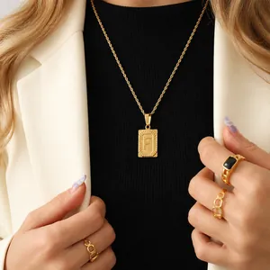 Set collana con lettera F quadrata e anelli geometrici dorati indossati da modella