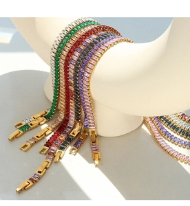 Detail of colorful rectangular zircon tennis bracelets with gold plated clasps on a model