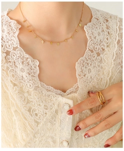 Detailed view of women's 18k gold leaf pendant choker necklace and matching ring on model