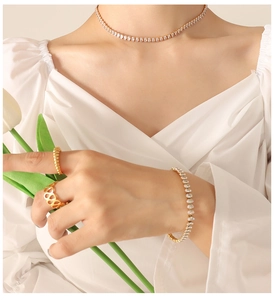 Close-up of gold-plated tennis necklace and bracelet set with geometric zircon rings