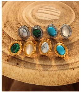Vintage ovale oorknoppen set met turkoois en kattenoogstenen op houten ondergrond