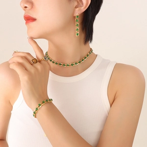 Set gioielli dorati con collane e orecchini in zircone verde su modella femminile