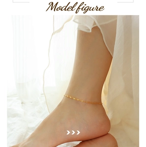 Detail of a minimalist gold leaf-shaped chain anklet worn on ankle in soft natural light