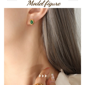 Primer plano de elegante pendiente de oro con piedra preciosa verde ovalada en la oreja