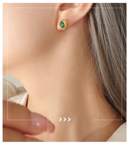 Detalle de aretes vintage de oro con piedra verde incrustada en la oreja del modelo