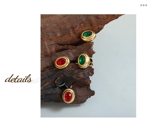 Detalle de pendientes vintage dorados con circonitas ovaladas en color rojo y verde