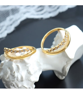 Primer plano de anillo doble dorado con circonitas sobre un busto de yeso blanco