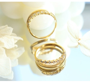 Primer plano de anillo chapado en oro 18k con circonitas reflejado en superficie lisa
