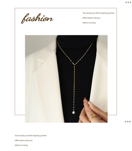 Detail van gouden lariat ketting met parel en bijpassende kristallen ring op model