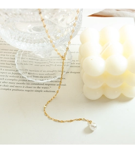 Macro-opname van goudkleurige Y-vormige ketting met elegante witte parelhanger detail
