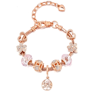 Detailed close-up of rose gold charm bracelet with flower, heart, and tree of life pendants