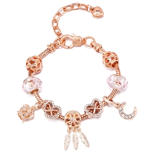 Detail of rose gold snake chain bracelet with crown, dreamcatcher, and pink crystal beads