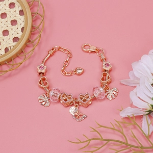 Close-up of rose gold charm bracelet with pink crystals and floral pendants on pink background