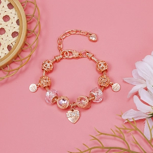 Close-up of rose gold charm bracelet with pink crystal beads and LOVE heart pendant
