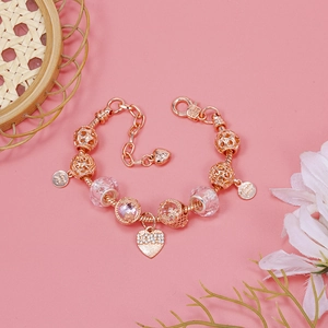 Macro detail of rose gold charm bracelet with pink crystals and heart pendants on pink decor