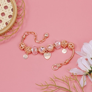 Macro shot of rose gold charm bracelet with pink faceted beads and Love heart pendant