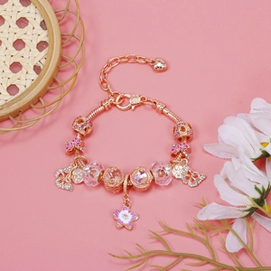 Macro detail of cherry blossom charm bracelet with rose gold snake chain and pink beads