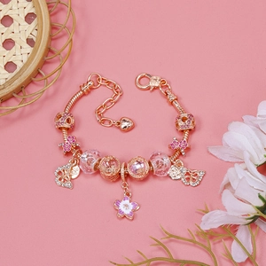 Rose gold snake chain bracelet with pink enamel flower and crystal charms on pink background