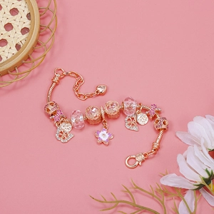 Macro detail of rose gold snake chain bracelet with pink enamel flower and crystal beads