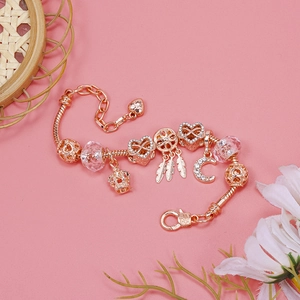 Detail of rose gold charm bracelet with crown, heart, and feather moon pendants