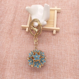 Detailed close-up of light blue floral ball keychain with golden alloy ring and clasp