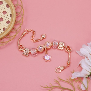 Detail of rose gold charm bracelet with cherry blossom and ferris wheel pendants
